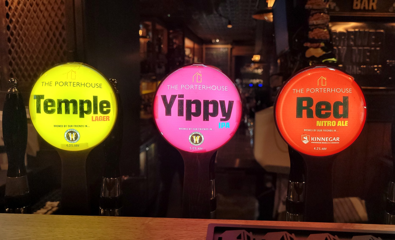 Three Porterhouse tap badges clearly showing the brewery of production for each beer